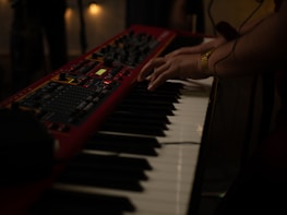 Close-up of hands playing a vintage synthesizer keyboard.