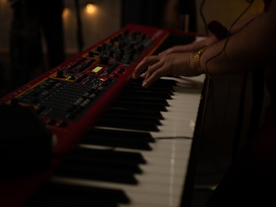 Close-up of hands playing an analog synthesizer with warm lighting.