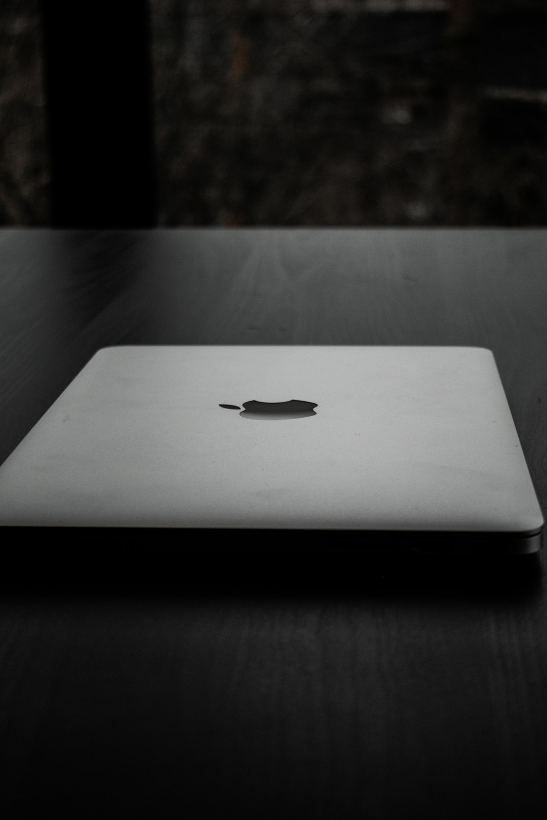 silver macbook on black table