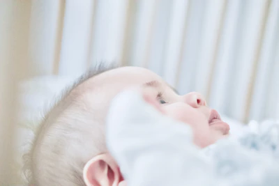 baby lying on white textile