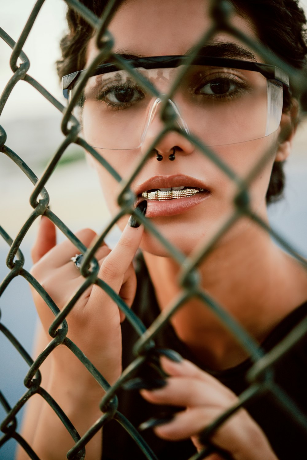 woman in red lipstick behind gray metal fence