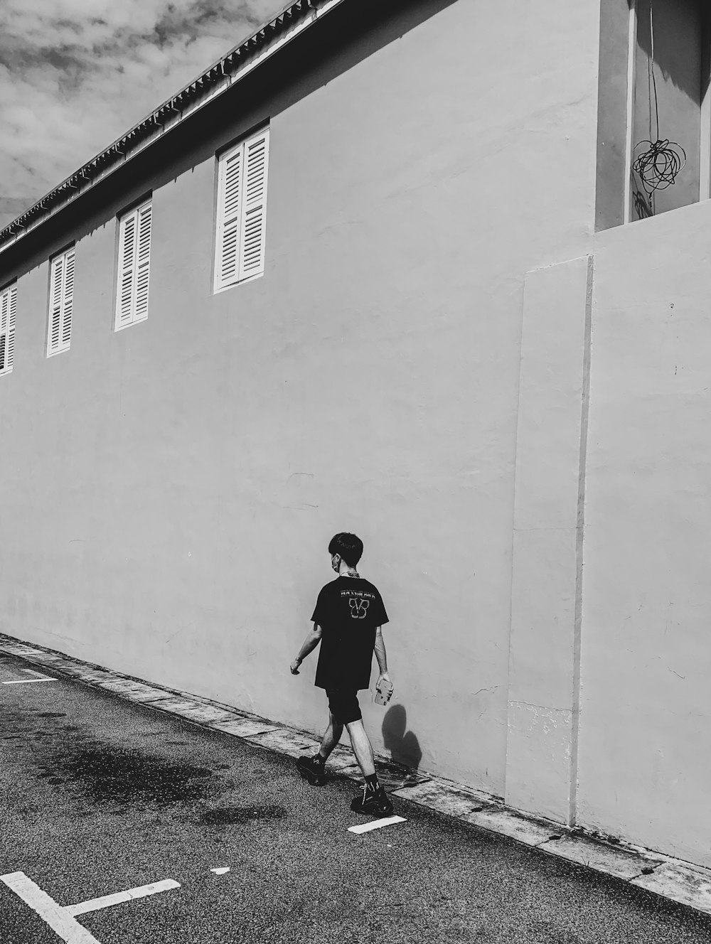 man in white shirt and black pants walking on sidewalk