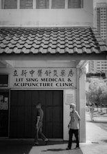 grayscale photo of man and woman walking on sidewalk