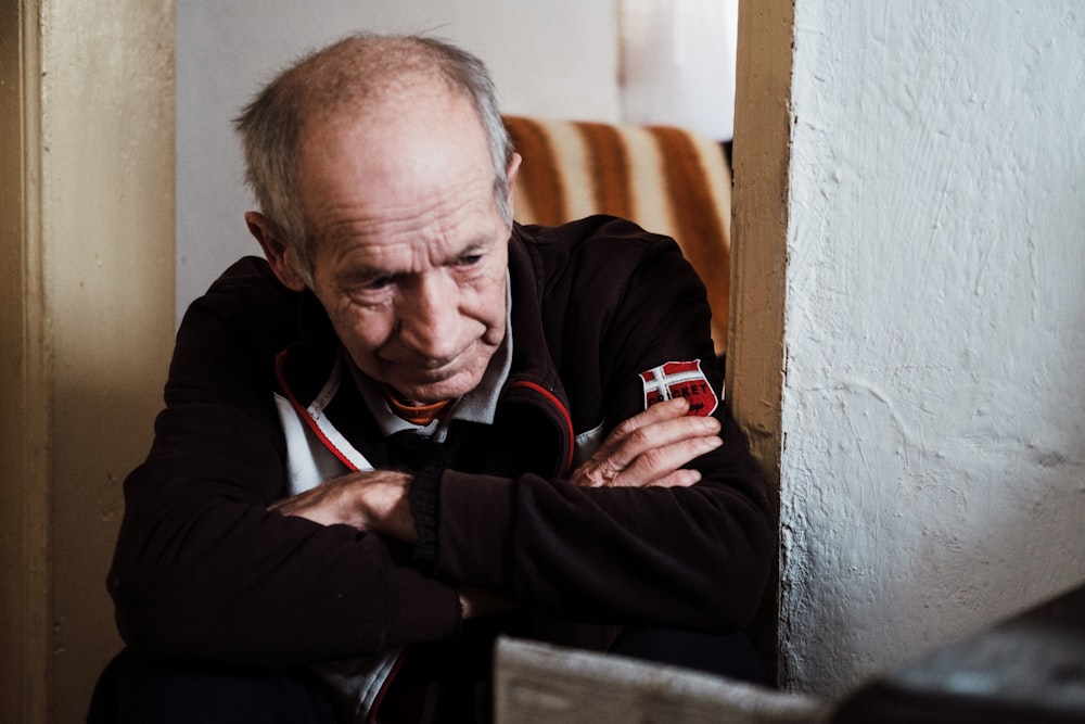 man in black jacket sitting on brown wooden chair