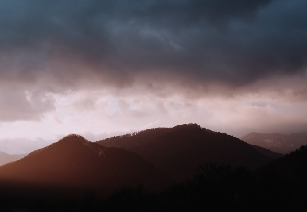 silhouette of mountain under cloudy sky during daytime