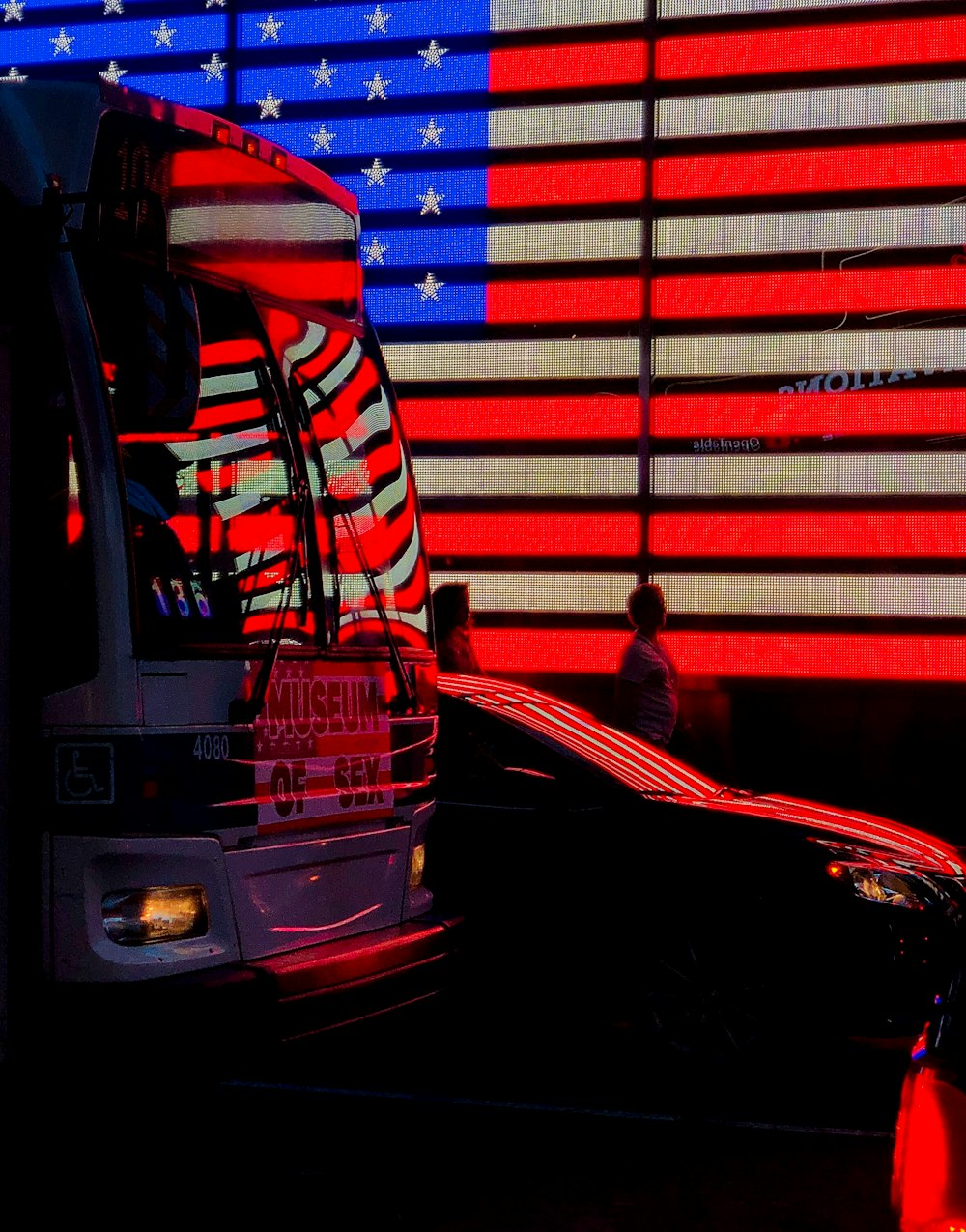 man in red jacket standing beside red bus during night time