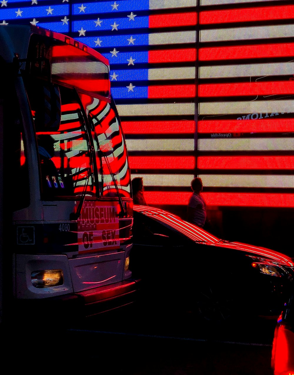 uomo in giacca rossa in piedi accanto all'autobus rosso durante la notte