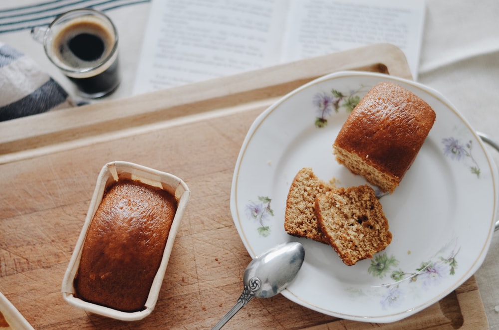 bread on white ceramic plate beside silver spoon