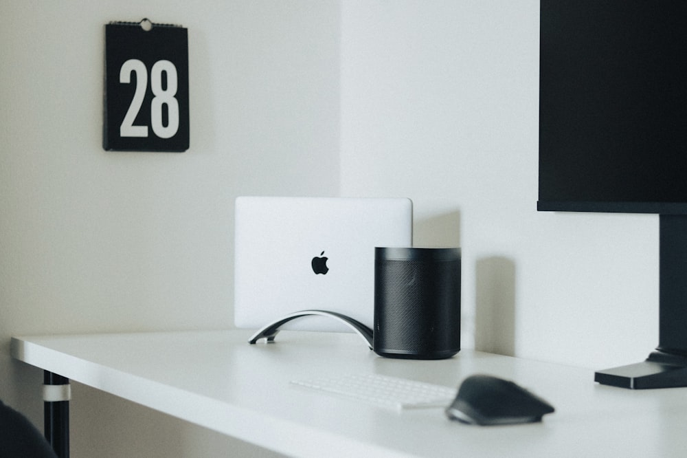 silver imac beside black and silver corded computer mouse on white wooden desk