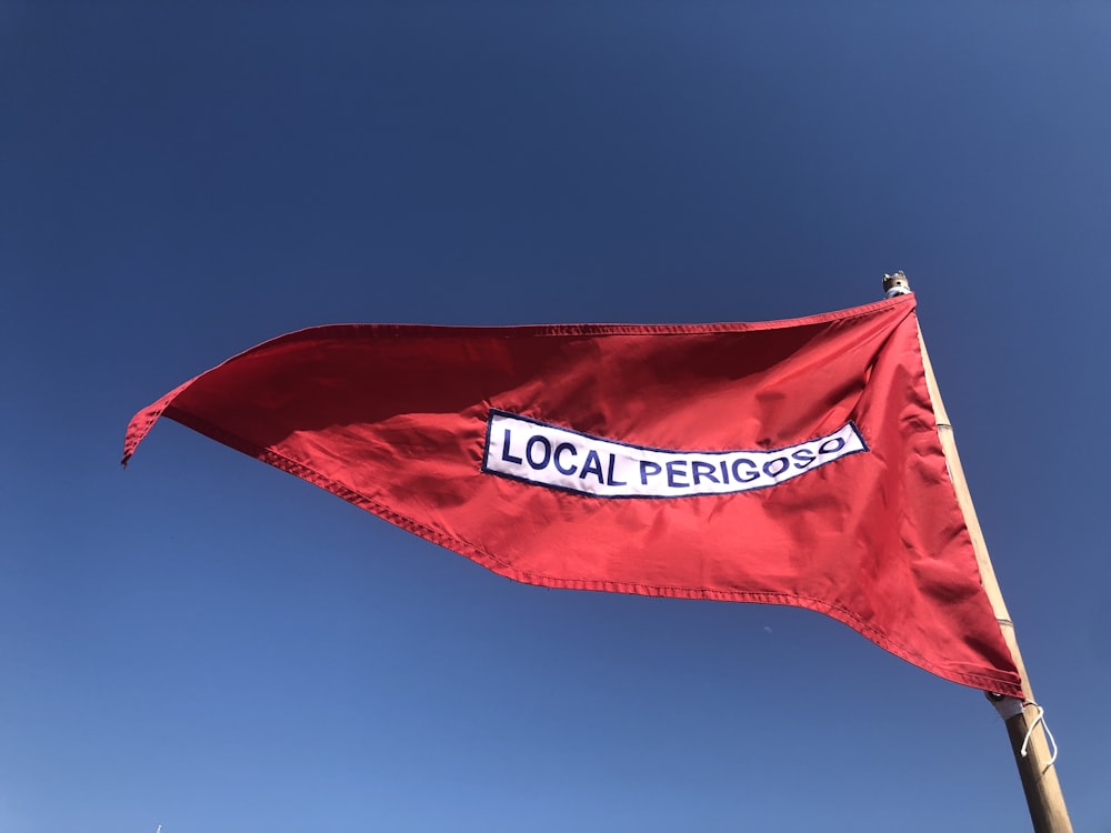 a red flag flying in the air with a blue sky in the background