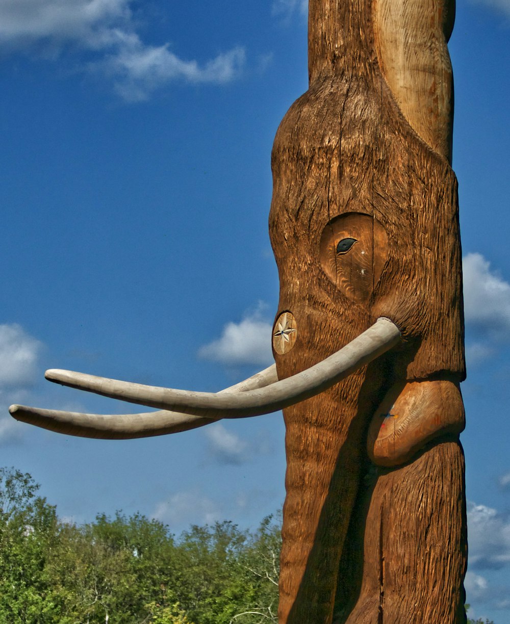 escultura de animal de madeira marrom perto de árvores verdes durante o dia
