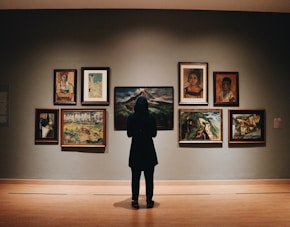 woman in black coat standing in front of paintings