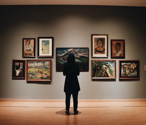 woman in black coat standing in front of paintings