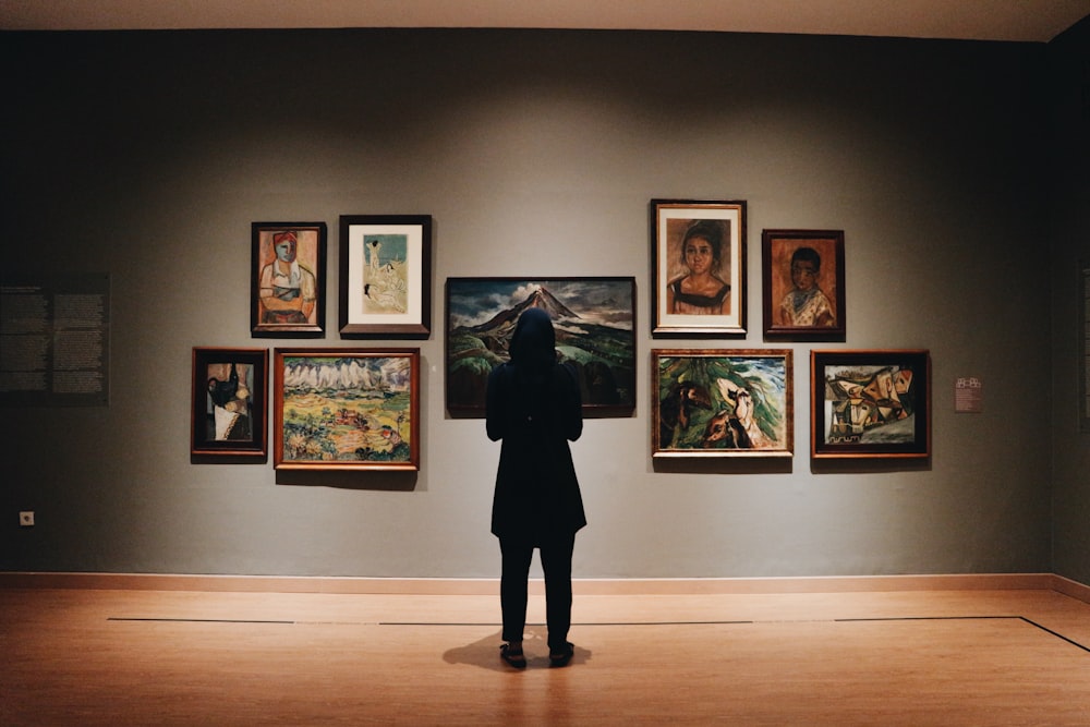 woman in black coat standing in front of paintings