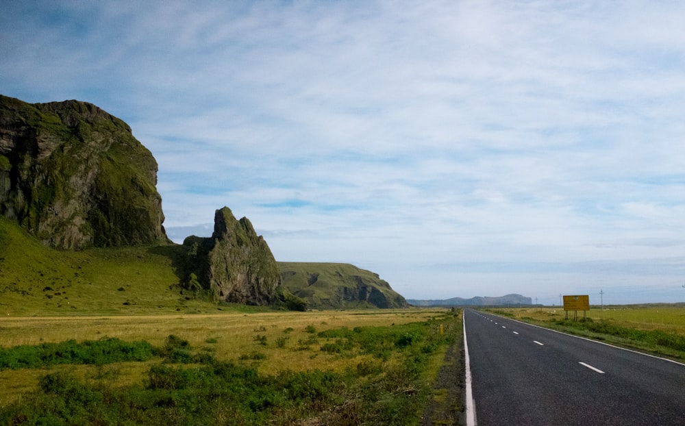 gray concrete road near green grass field during daytime