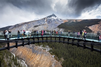 people standing on bridge near mountain during daytime