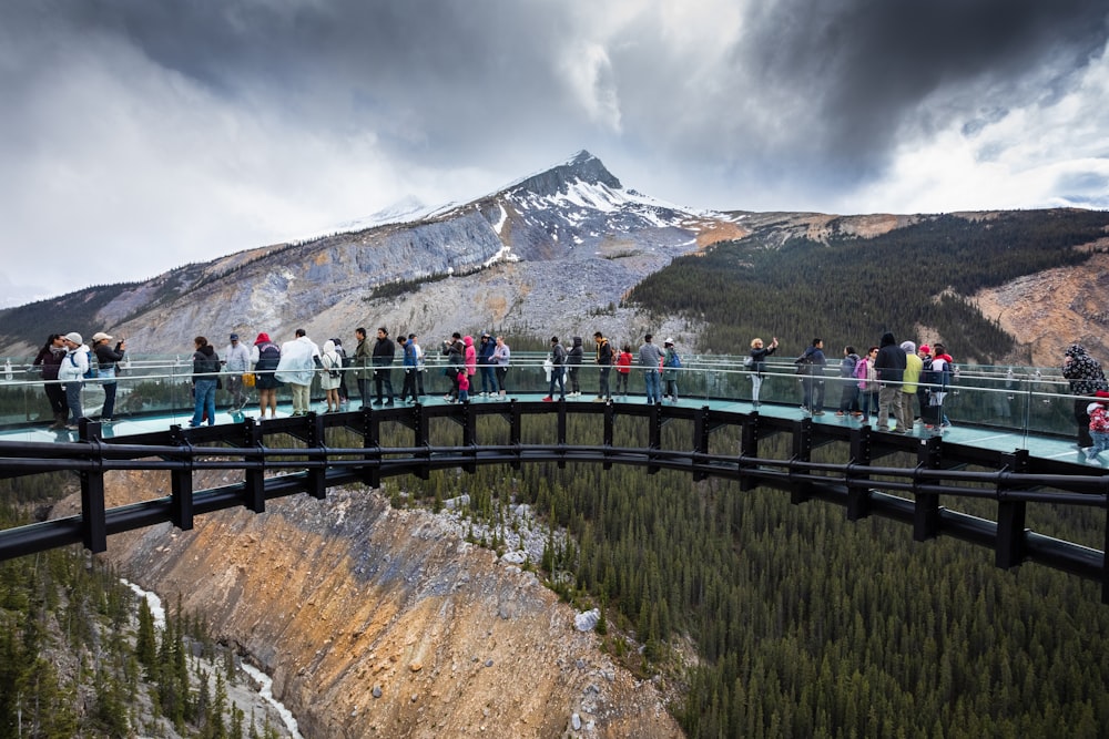 Personas de pie en un puente cerca de la montaña durante el día