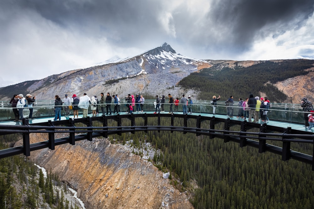 people standing on bridge near mountain during daytime