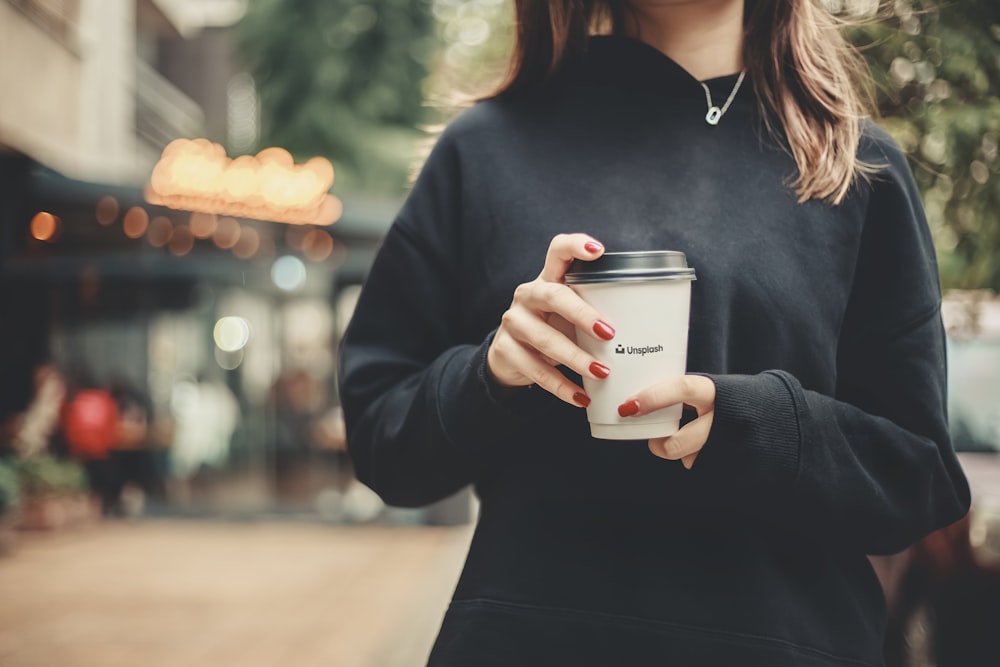 woman in black long sleeve shirt holding white ceramic mug