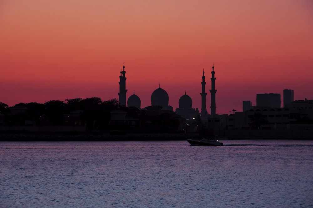 silhouette of building near body of water during sunset