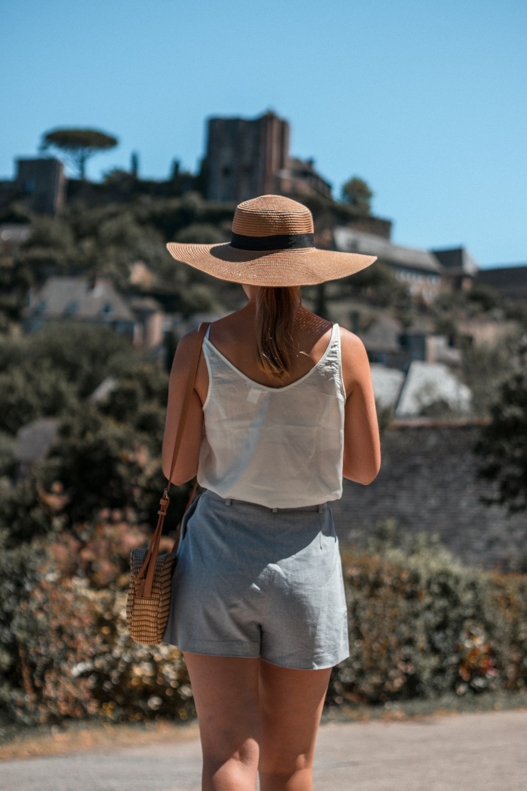 woman in white tank top and white skirt wearing brown straw hat
