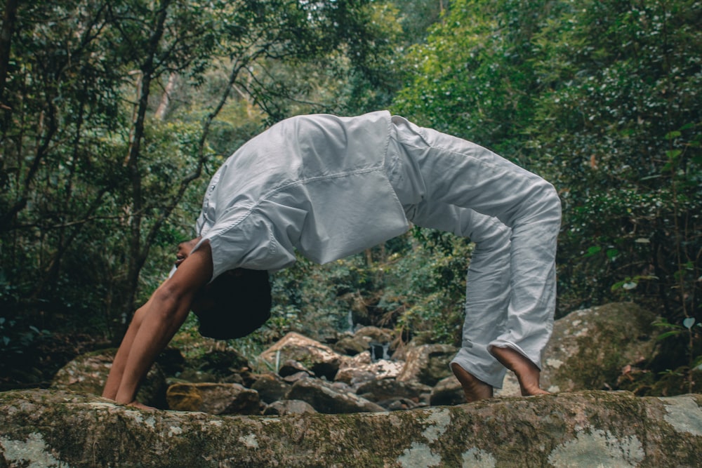 man in white long sleeve shirt and white pants standing on rocky ground