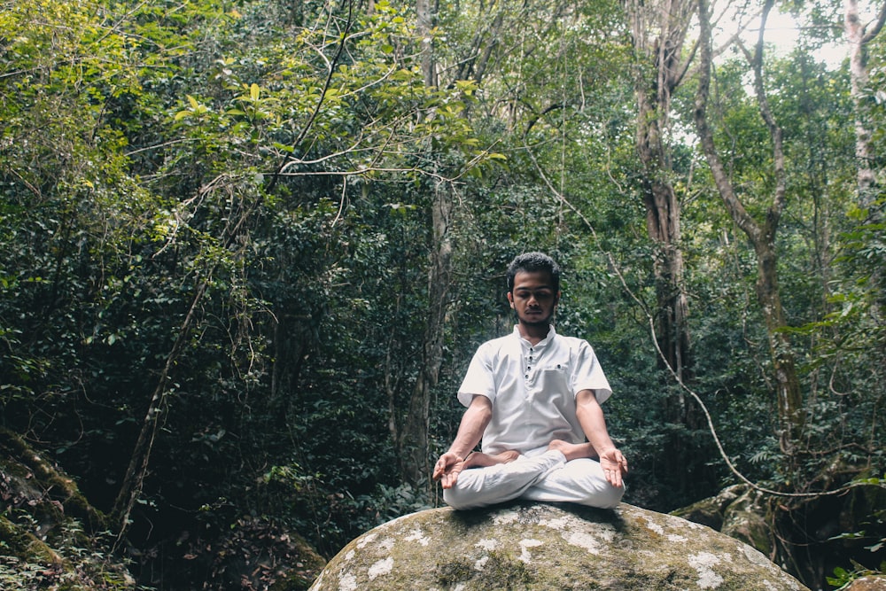 man in white polo shirt sitting on rock