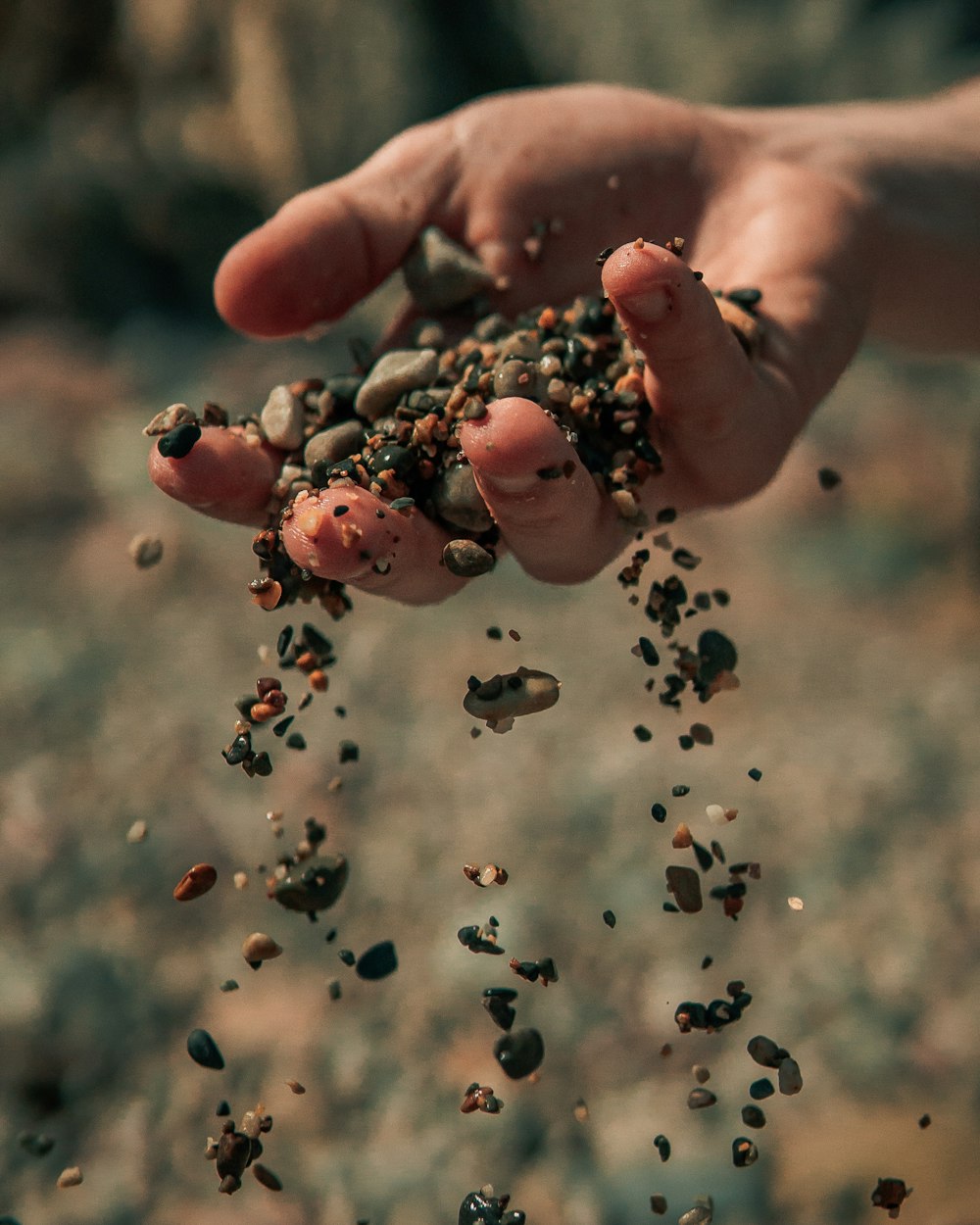 person holding silver beads in tilt shift lens