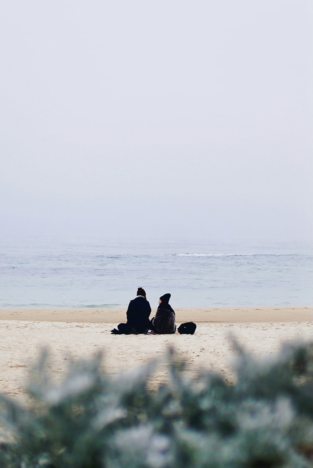 2 Personen sitzen tagsüber am Strand