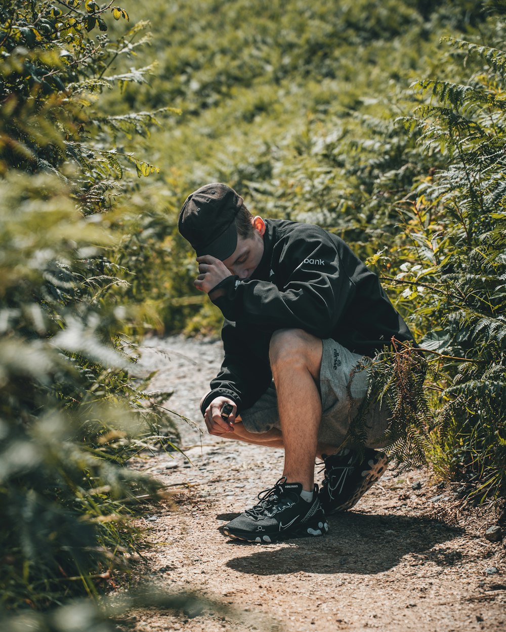 man in black t-shirt and brown shorts sitting on ground during daytime