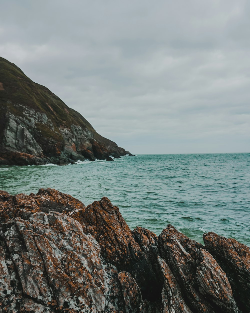 brown rock formation on sea under white clouds during daytime