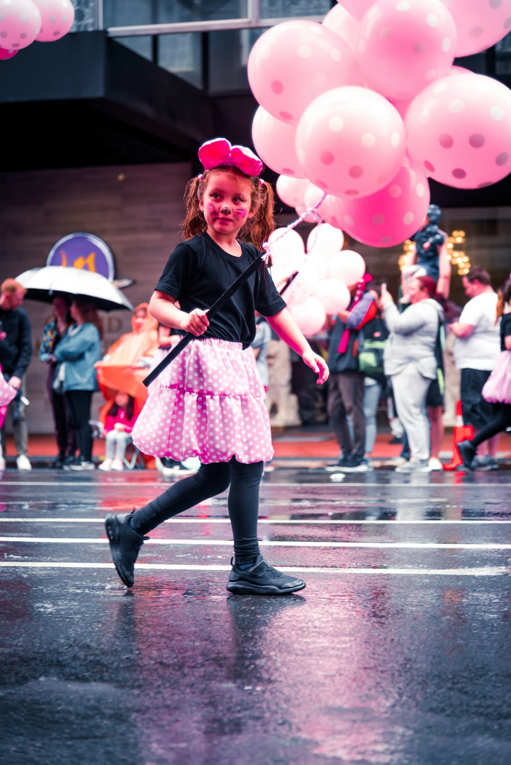 girl in black jacket and pink skirt with pink hat holding umbrella