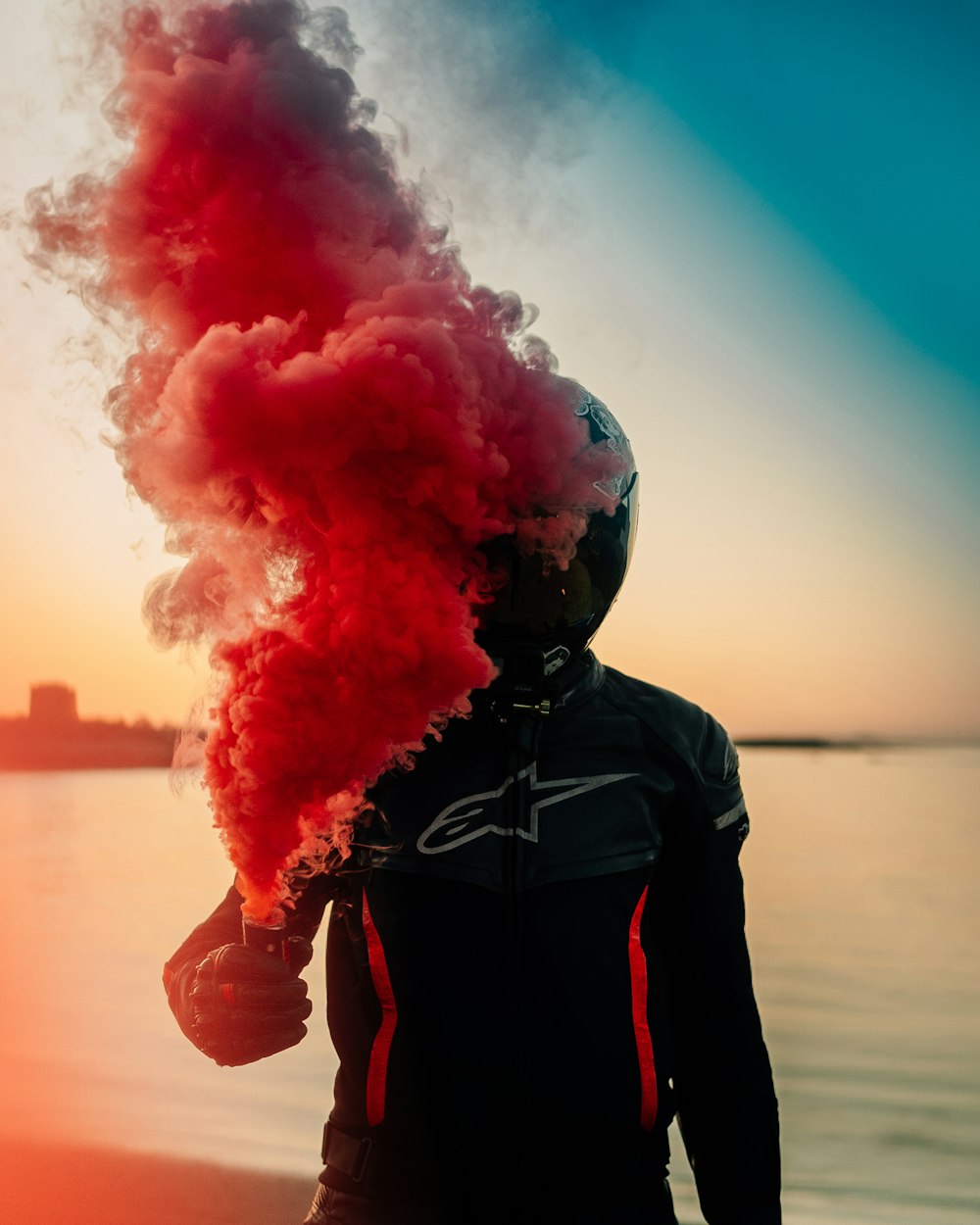 person in black hoodie with red smoke on his face