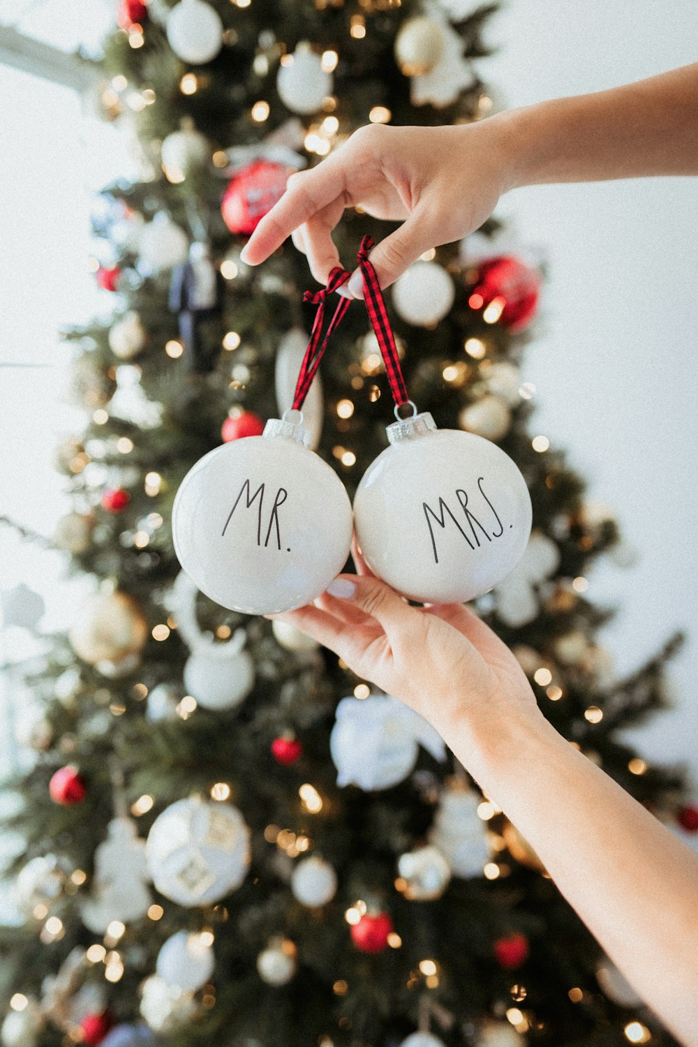person holding white and red christmas baubles