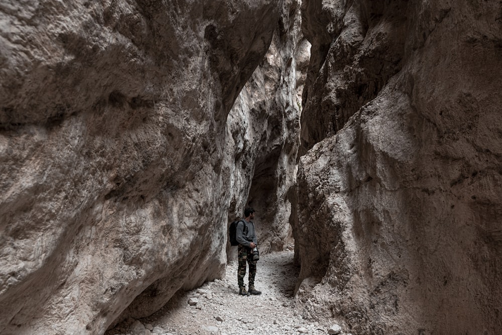 man in blue jacket and black pants walking on rocky road during daytime