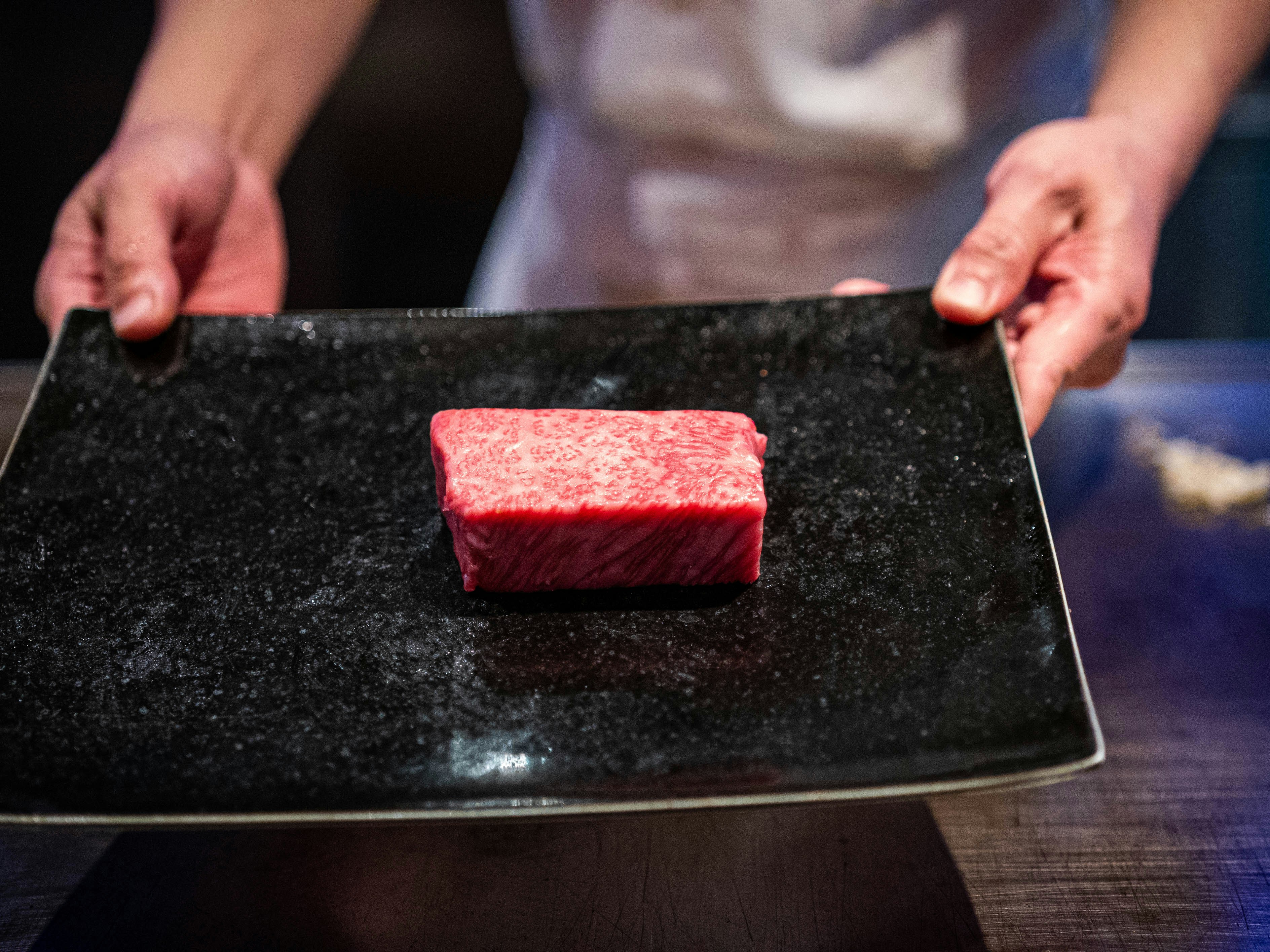 person holding black wooden chopping board