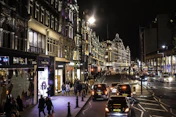 people walking on sidewalk near cars and buildings during night time