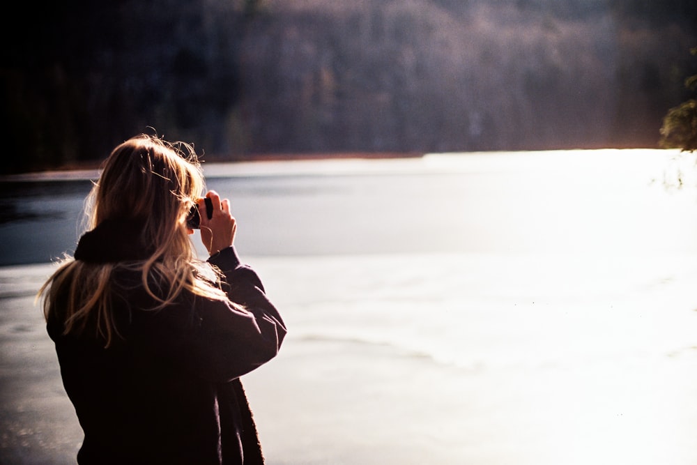 woman in black coat standing on snow covered ground during daytime