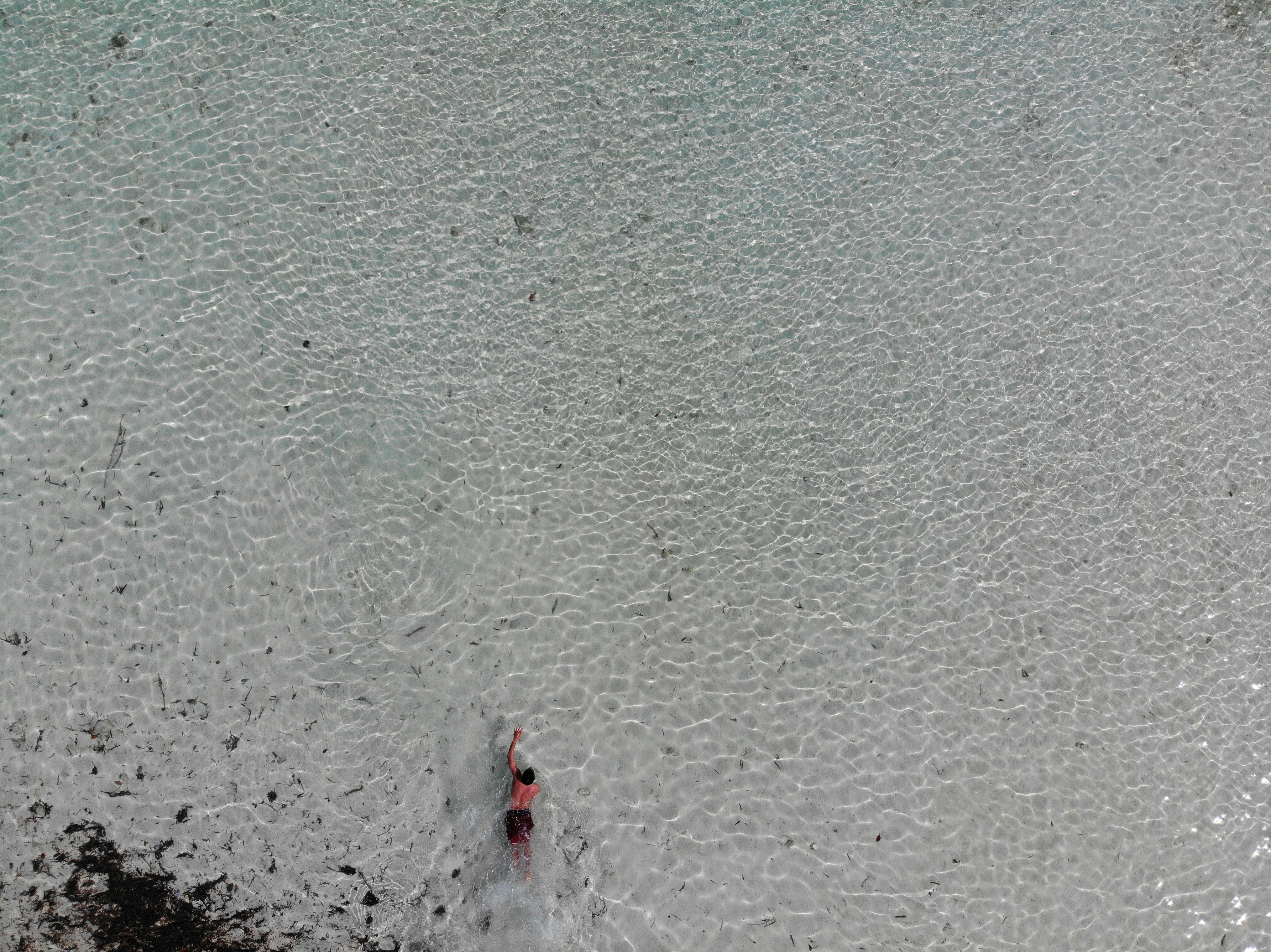 person in red shirt standing on beach during daytime