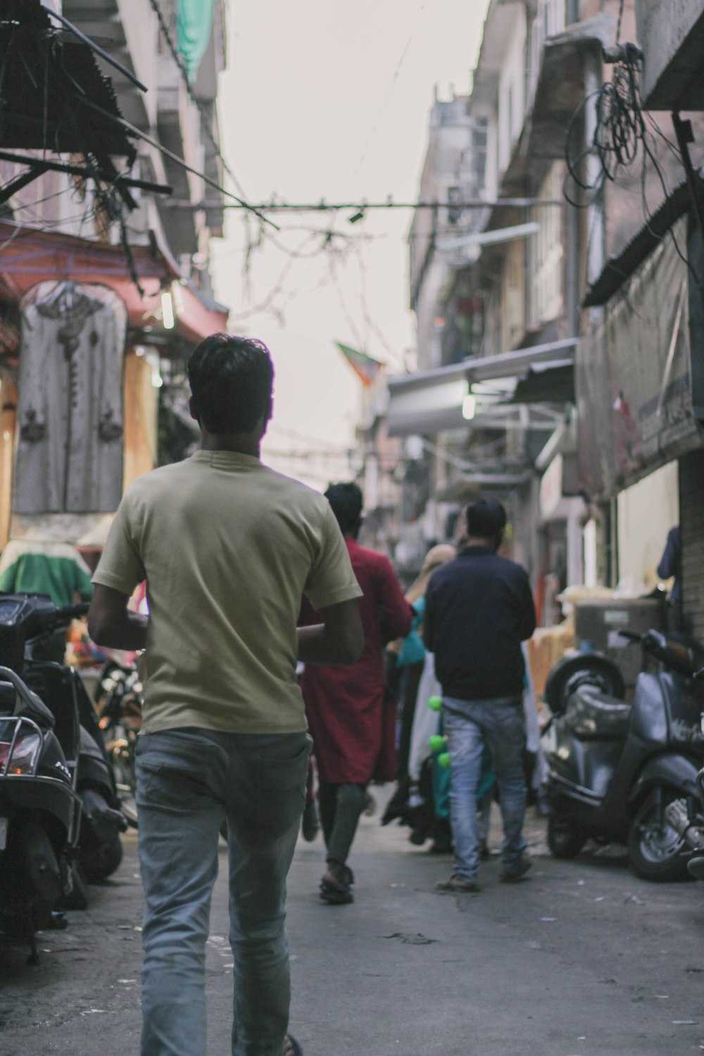 man in green jacket walking on street during daytime