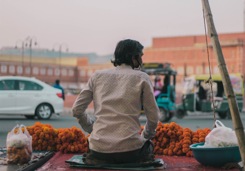 woman in pink sweater standing in front of fruit stand during daytime