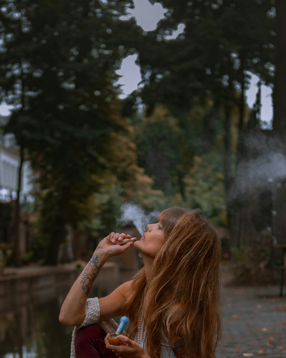Mujer fumando cerca de árboles verdes durante el día