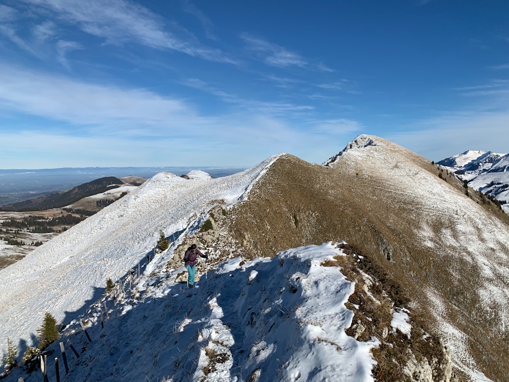 people hiking on snow covered mountain under blue sky during daytime