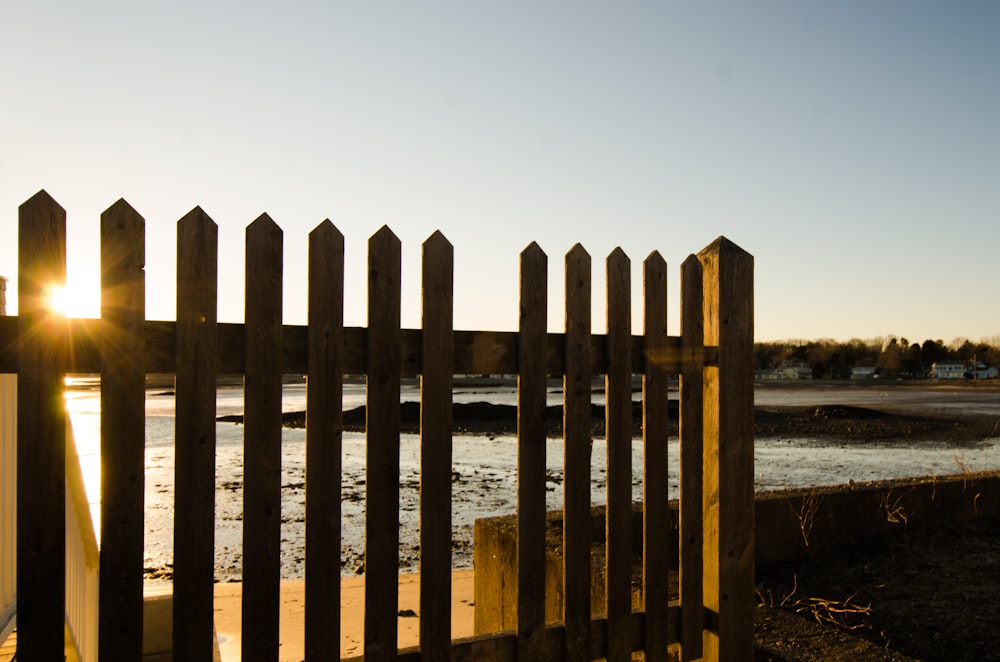 brown wooden fence on sea shore during daytime