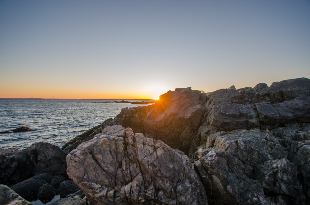 brown rocky mountain near sea during sunset