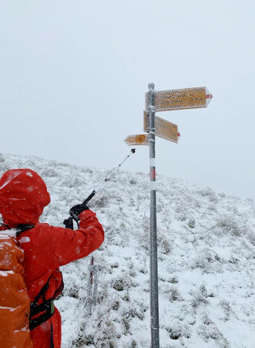 person in red jacket and red helmet holding black metal stick
