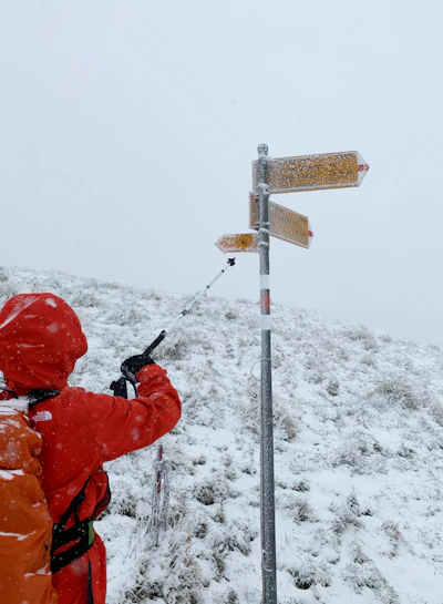 person in red jacket and red helmet holding black metal stick