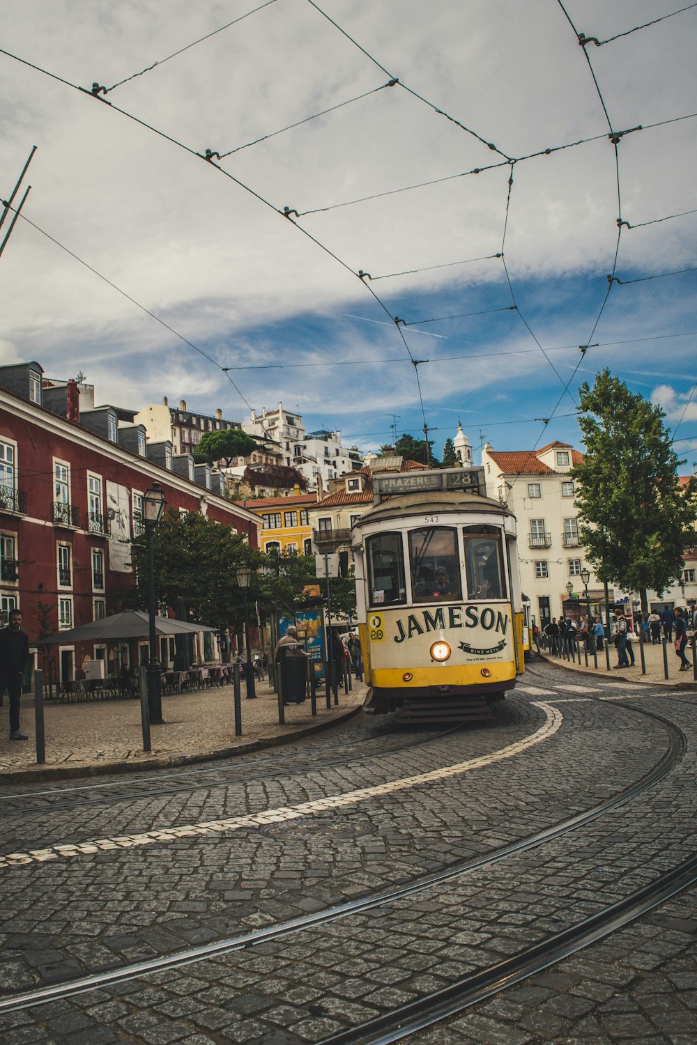 yellow and white tram on road near brown concrete building during daytime