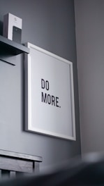 a picture hanging on a wall with a do more sign above it