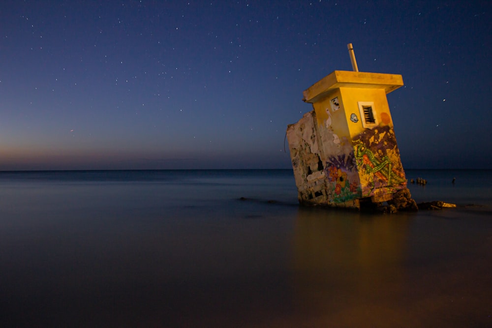 brown concrete building on brown rock formation on sea under blue sky during night time